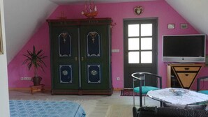 Una habitación con un armario grande, un televisor, una mesita con un frutero y una planta en maceta.