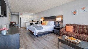 Et moderne hotelværelse med seng, sofa, spisebord og tekøkken.