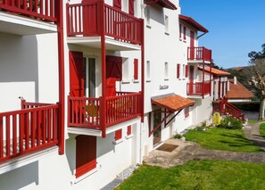 A multi-story building with balconies, a stone pathway, and a well-maintained lawn. - Homerez - Studio in Guéthary (Guéthary)