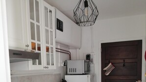 Une cuisine compacte équipée d’un lave-linge, d’un four à micro-ondes et d’une machine à café.