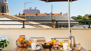A breakfast table set outdoors with a view of buildings in the background.