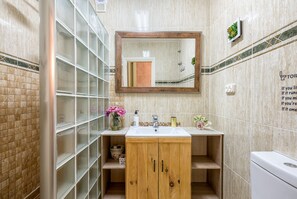 Bathroom features a large mirror, sink, and toilet, with a cabinet and potted plant.