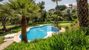 A swimming pool surrounded by lush greenery and palm trees.