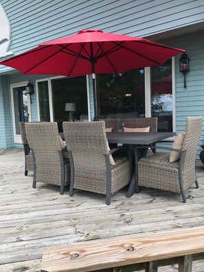 Une terrasse avec une table et des chaises, un parasol rouge et une plateforme en bois.