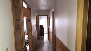 A narrow hallway with wooden paneling on the walls and a tiled floor. - Waterfront Vacation Home Directly on Hubbard Lake - East Shore (Spruce)