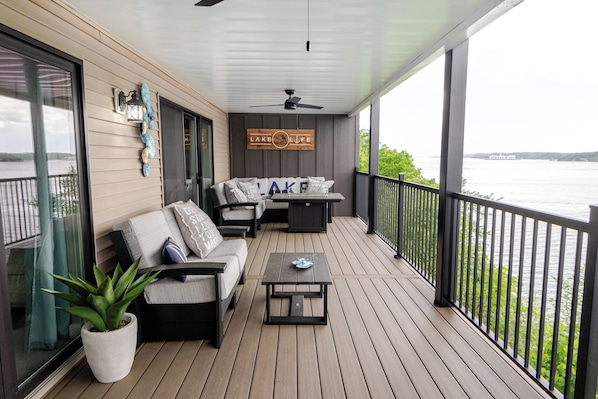 A covered deck with a sofa, a coffee table, and a sign that reads 'LAKE LIFE'.