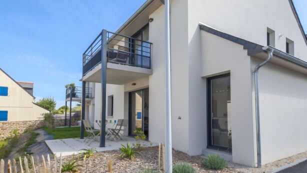 A modern two-story house with a balcony, a garage, and a well-maintained garden.