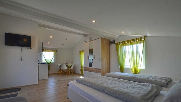 A modern hotel room with two beds, a kitchenette, a dining area, and a TV. - Bavica studio with private parking (Rovinj)