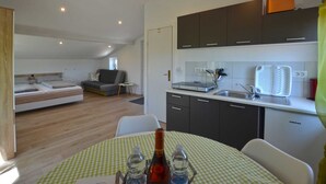 A compact living space with a kitchenette, a dining area, and a bedroom with a loft bed. - Bavica studio with private parking (Rovinj)