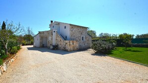 A stone building with a gravel driveway and a green lawn. - Bavica studio with private parking (Rovinj)