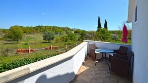 A balcony with a table and chairs, overlooking a green landscape with trees and a clear sky. - Bavica studio with private parking (Rovinj)
