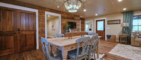 Un coin repas avec une table et des chaises en bois, un lustre et un tapis en peau de vache.