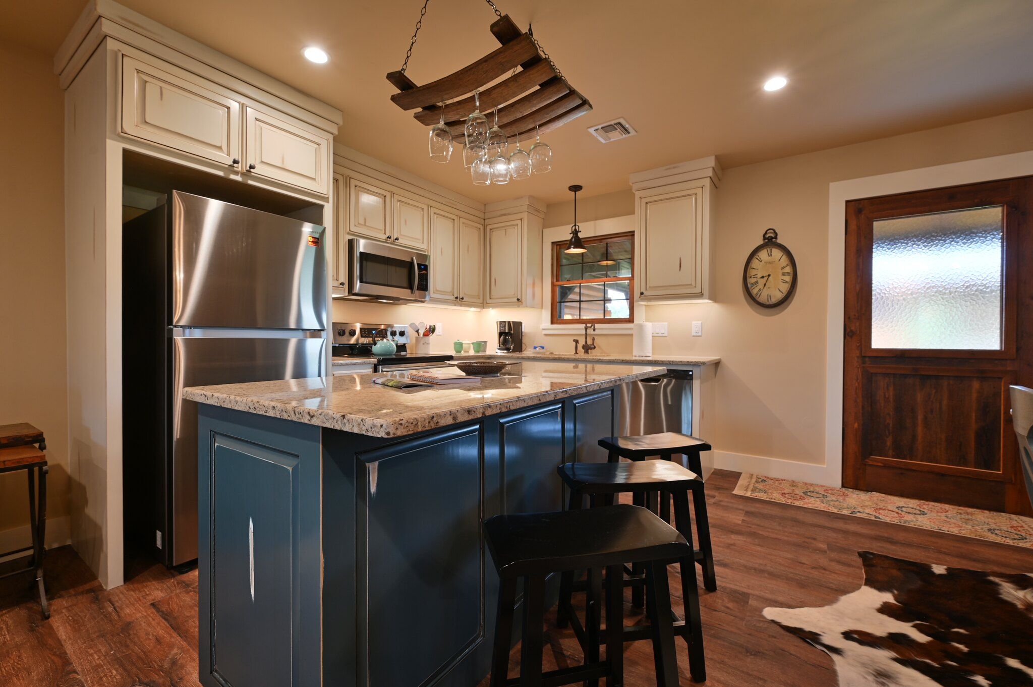 A kitchen with a central island, stainless steel appliances, and a clock on the wall.