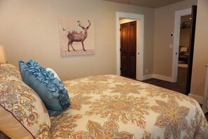 Un dormitorio con una colcha estampada, un cojín decorativo y un cuadro de un ciervo colgado en la pared.