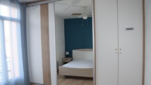 Ein Schlafzimmer mit Bett, Kleiderschrank, Deckenventilator und Nachttisch.