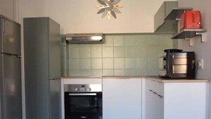 Eine kleine Küche mit einbauendem Backofen, einer Mikrowelle und einem Kühlschrank.
