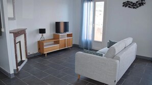 Ein Wohnzimmer mit Sofa, Fernseher, einer Holz-Unterhaltungseinheit und Fisch-Wandbild.