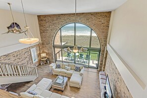 Relax in a spacious room with a high ceiling, large arched window, and comfortable seating area.