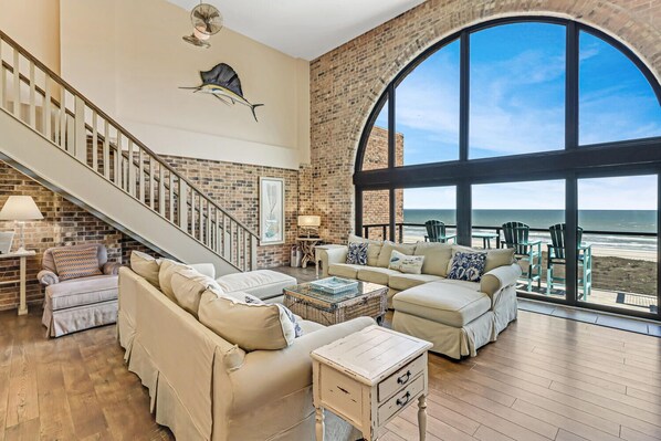 Enjoy a serene ocean view from the high ceiling and large arched window in this spacious living area.