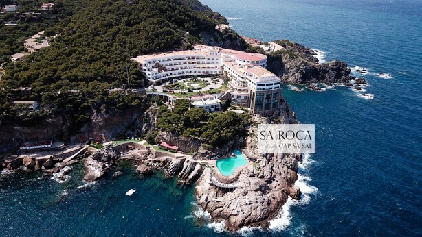 Un hôtel en bord de mer, doté d’une piscine, entouré de falaises rocheuses et donnant sur la mer.