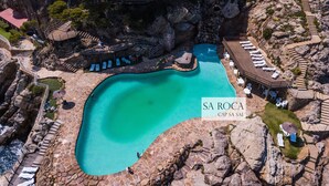 Une grande piscine entourée d’un paysage rocheux, avec des chaises longues et une terrasse en bois.