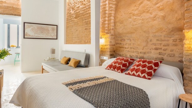 Une chambre moderne avec un grand lit, un bureau et une chaise. Il y a une fenêtre donnant sur l’extérieur.