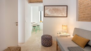 Un salon moderne avec un canapé gris, un pouf à motifs, une lampe sur pied et une carte encadrée accrochée au mur.