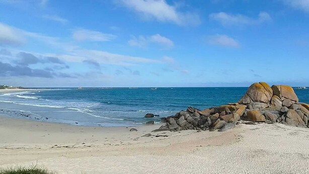 A beach with a rocky outcrop in the foreground and a clear blue sky. - Homerez - House in Cléder. (Cléder)