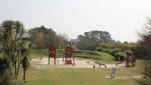A playground with slides and climbing structures, surrounded by grass and trees. - Homerez - House in Cléder. (Cléder)