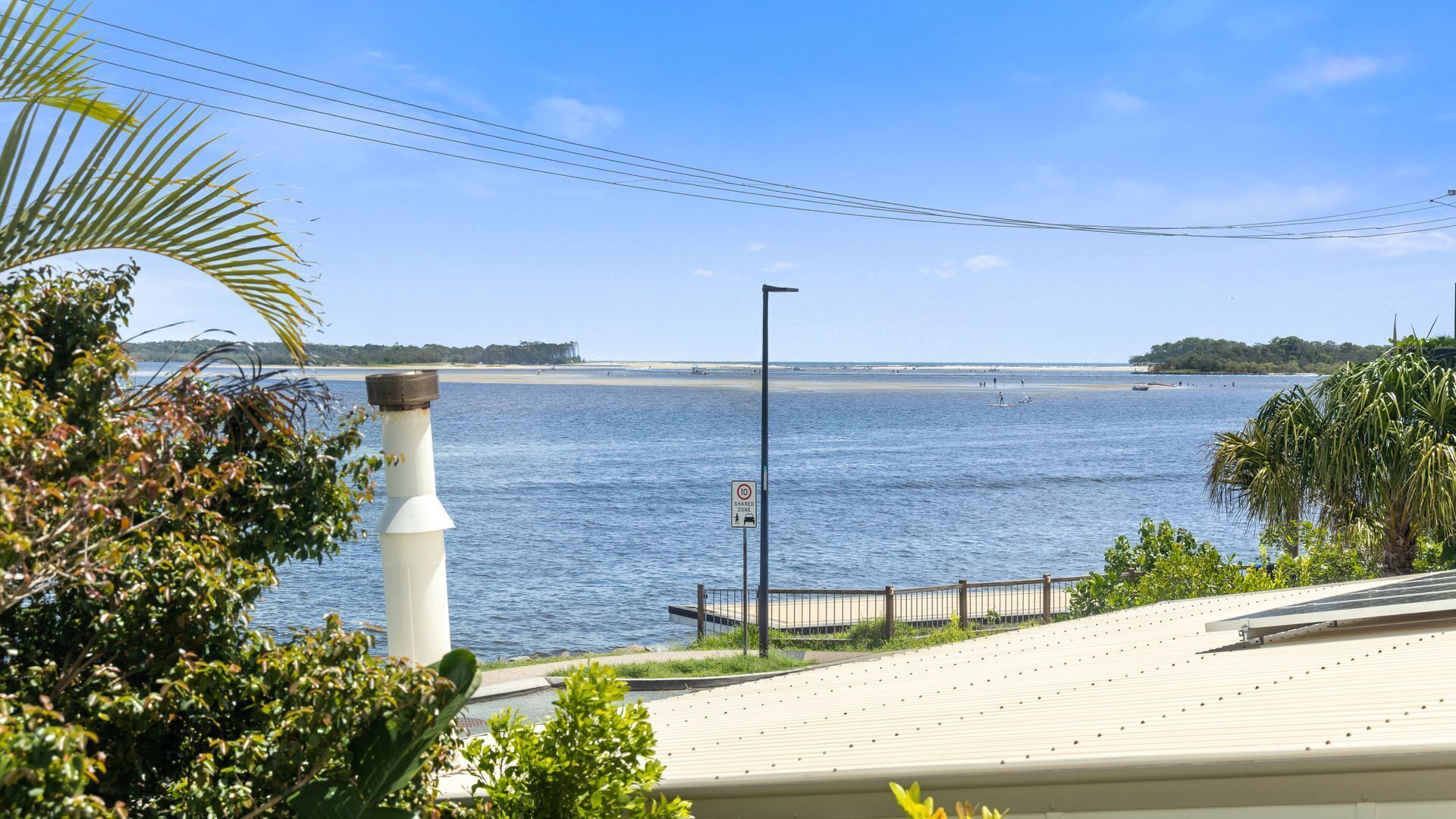 A coastal view with a beach, a lighthouse, and a shared zone sign.