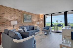 A modern living room with a brick wall, a large window, and a view of the outdoors.