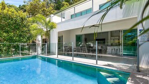 A modern building with a swimming pool, outdoor seating, and a glass-enclosed patio.