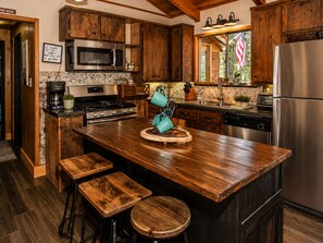 A kitchen with wooden cabinets, a stainless steel refrigerator, a built-in microwave, and a granite countertop.