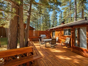 Eine Hütte mit Terrasse, Sitzgelegenheit im Freien und Grill.