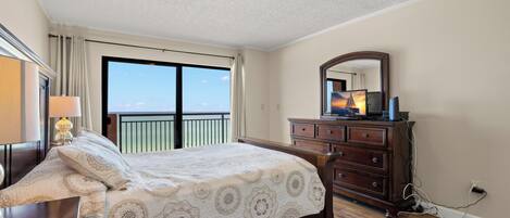 A bedroom with a bed, dresser, and a large window with a view.