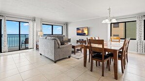 A modern living room with a sofa, dining table, chairs, and a TV.