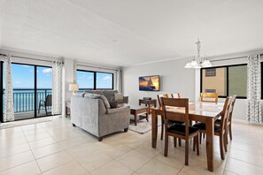 A modern living room with a sofa, dining table, chairs, and a TV.