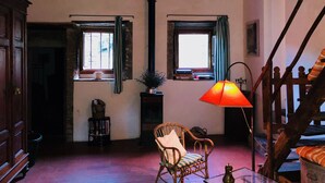 Ein gemütliches Zimmer mit Holzboden, einem Korbsessel, einem Tisch mit Lampe und einer Treppe.