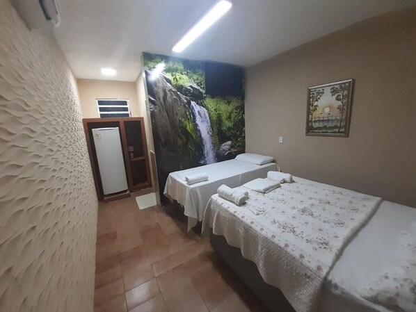 A room with two beds, a shower area, and a mural of a waterfall. - Hotel Nacional (Sobral)
