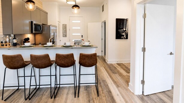 A modern kitchen with a bar area, stainless steel appliances, and a 'WELCOME' sign.