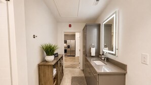 A modern bathroom with a large mirror, a sink, and a wooden vanity. - Comfortable condo near Vanderbilt with easy access to local attractions (Nashville)