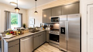 A modern kitchen with stainless steel appliances, a dishwasher, and a wooden floor. - Comfortable condo near Vanderbilt with easy access to local attractions (Nashville)