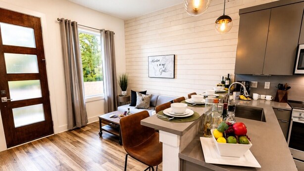 A modern kitchen with a dining area, wooden flooring, and a view of greenery outside. - Comfortable condo near Vanderbilt with easy access to local attractions (Nashville)