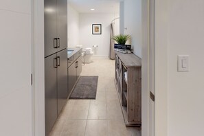 Un pasillo estrecho con una zona de cocina que cuenta con muebles modernos, un lavamanos y un armario de madera con un letrero que dice 'Nashville, TN'.