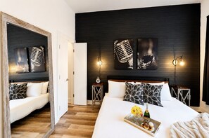 Een moderne hotelkamer met een groot bed, een spiegel, een donker houten hoofdeinde en kunstwerken aan de muur.