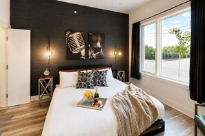 Een moderne slaapkamer met een groot bed, twee nachtkastjes en een raam met gordijnen.