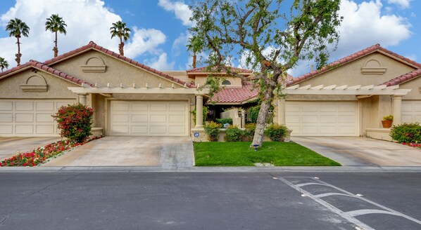 A residential property with two garages, a well-maintained lawn, and a clear sky. - WOW! Gorgeous Desert Condo Woodhaven Country Club (Palm Desert)