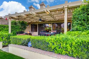 A covered patio area with outdoor seating, a pergola, and a well-maintained hedge. - WOW! Gorgeous Desert Condo Woodhaven Country Club (Palm Desert)