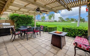 An outdoor patio with a grill, chairs, and a fire pit. - WOW! Gorgeous Desert Condo Woodhaven Country Club (Palm Desert)