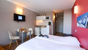 Ein Hotelzimmer mit Bett, Schreibtisch mit Stuhl, Mikrowelle und Fernseher.